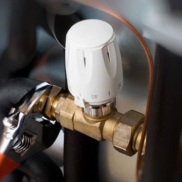 Handwerker loest eine Verschraubung an Heizungsventil