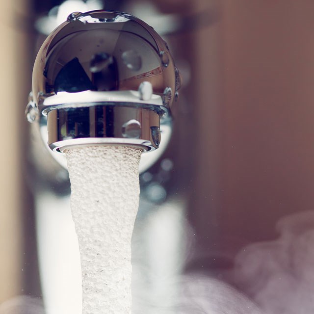 Wasserhahn mit fließendem heissen Wasser
